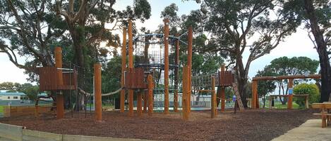 Un parque infantil con estructuras para escalar y una zona de acolchado alrededor.