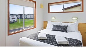 A hotel room with a bed, two bedside tables, a window, and a mirror.