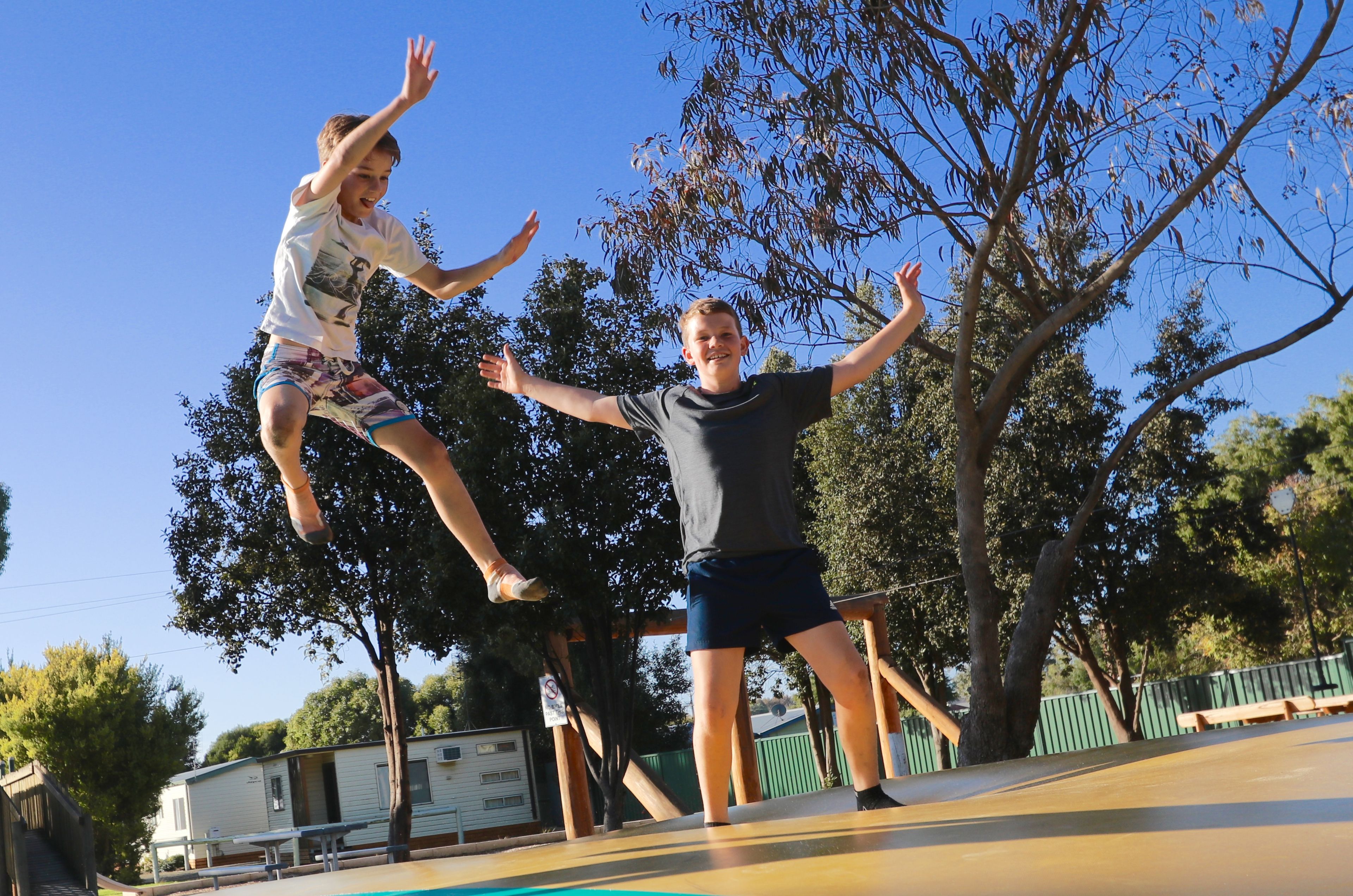 A trampoline park with a clear sky and trees in the background.
