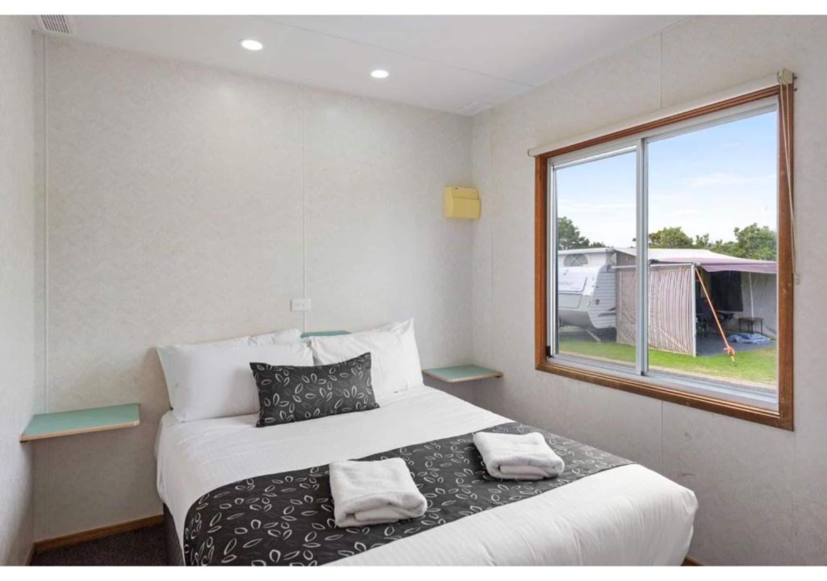 Una habitación de hotel con cama, ventana y una pequeña mesa.