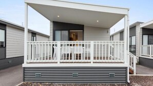 A modern outdoor balcony with a white railing, a table, and chairs.
