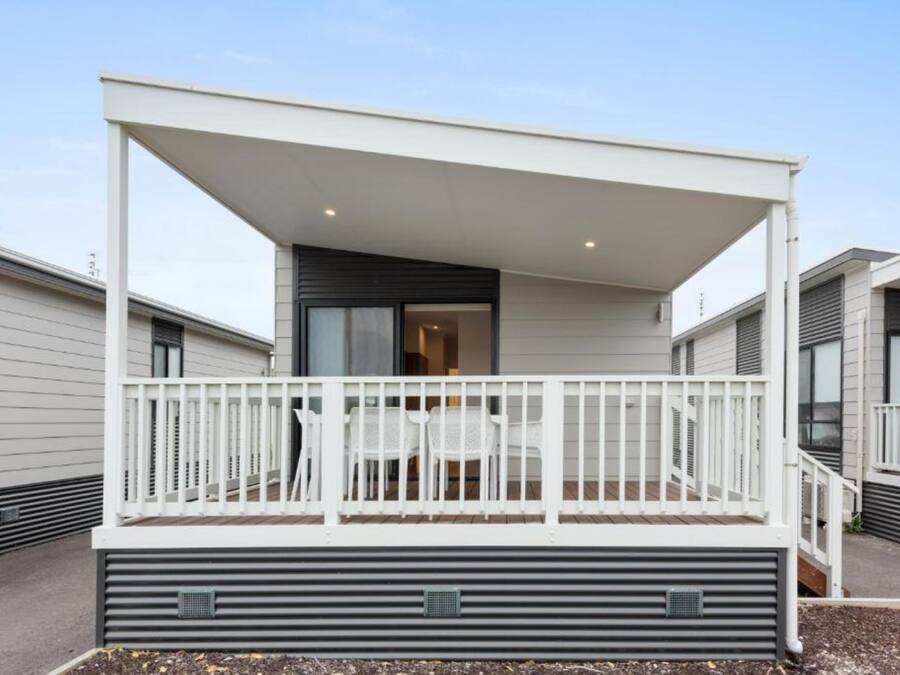 Un balcon extérieur moderne avec une balustrade blanche, une table et des chaises.