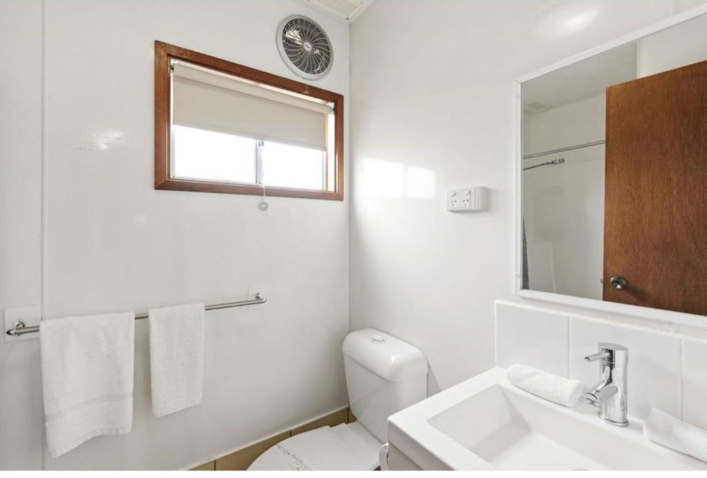 Un baño con inodoro, lavamanos y espejo.