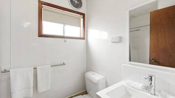 Un baño con inodoro, lavamanos y espejo.