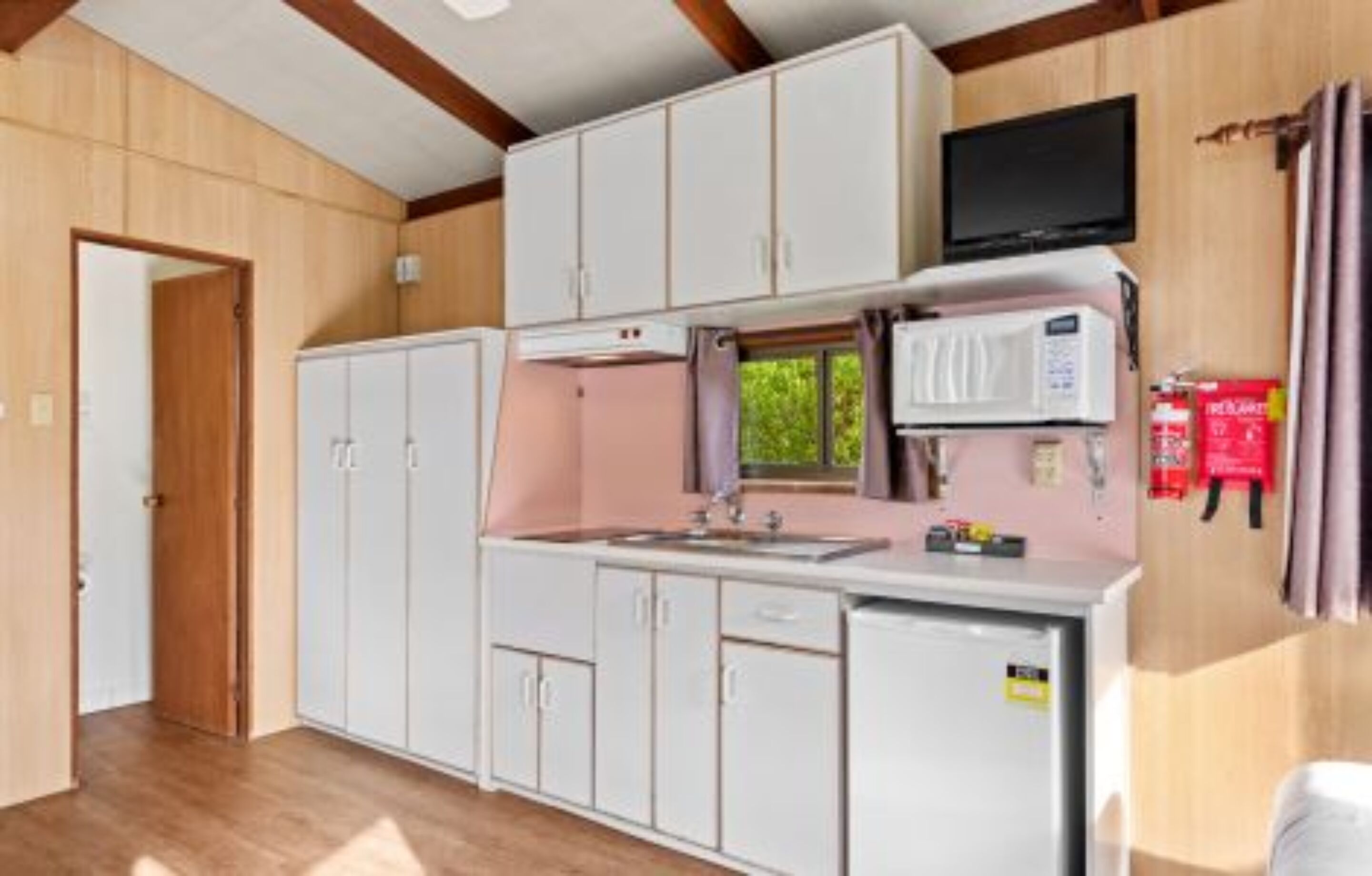 A compact kitchen with white cabinets, a microwave, and a small refrigerator.