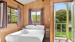 Un dormitorio con una cama grande, una mesita de noche y un ventanal corredero que da a un espacio exterior.