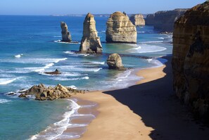 A coastal landscape with prominent rock formations and a sandy beach.