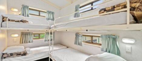A bunk bed room with two beds, each with a window and curtains.