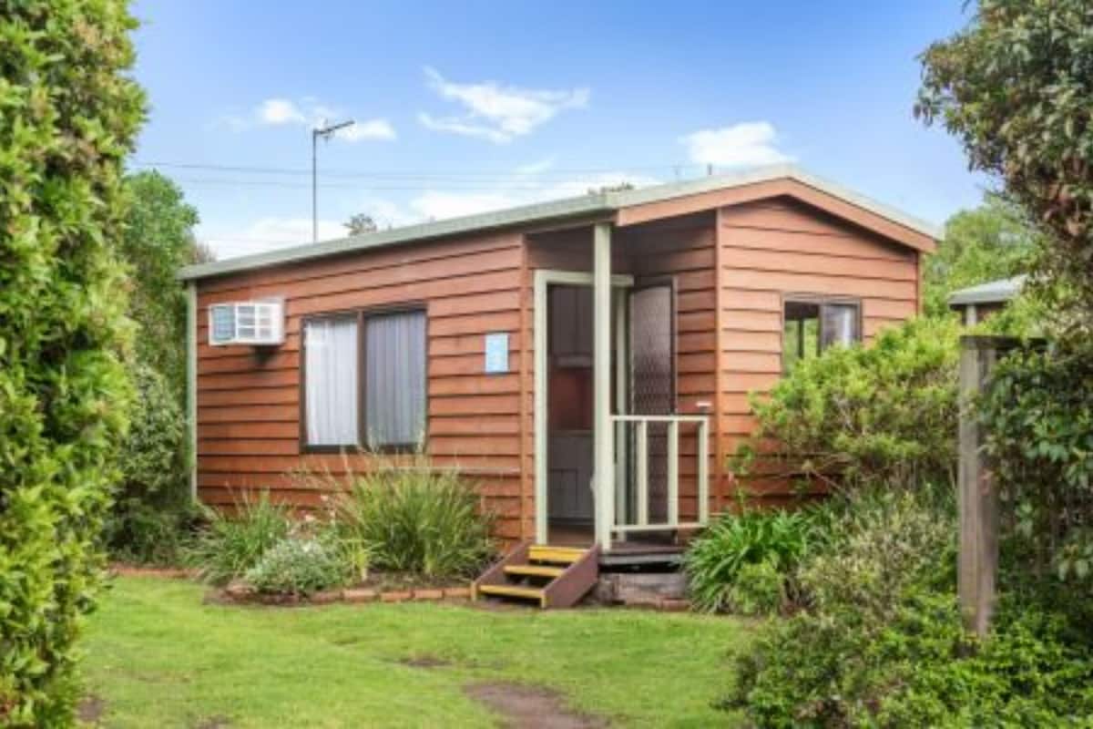 A single-story wooden house with a front porch and a small garden area.