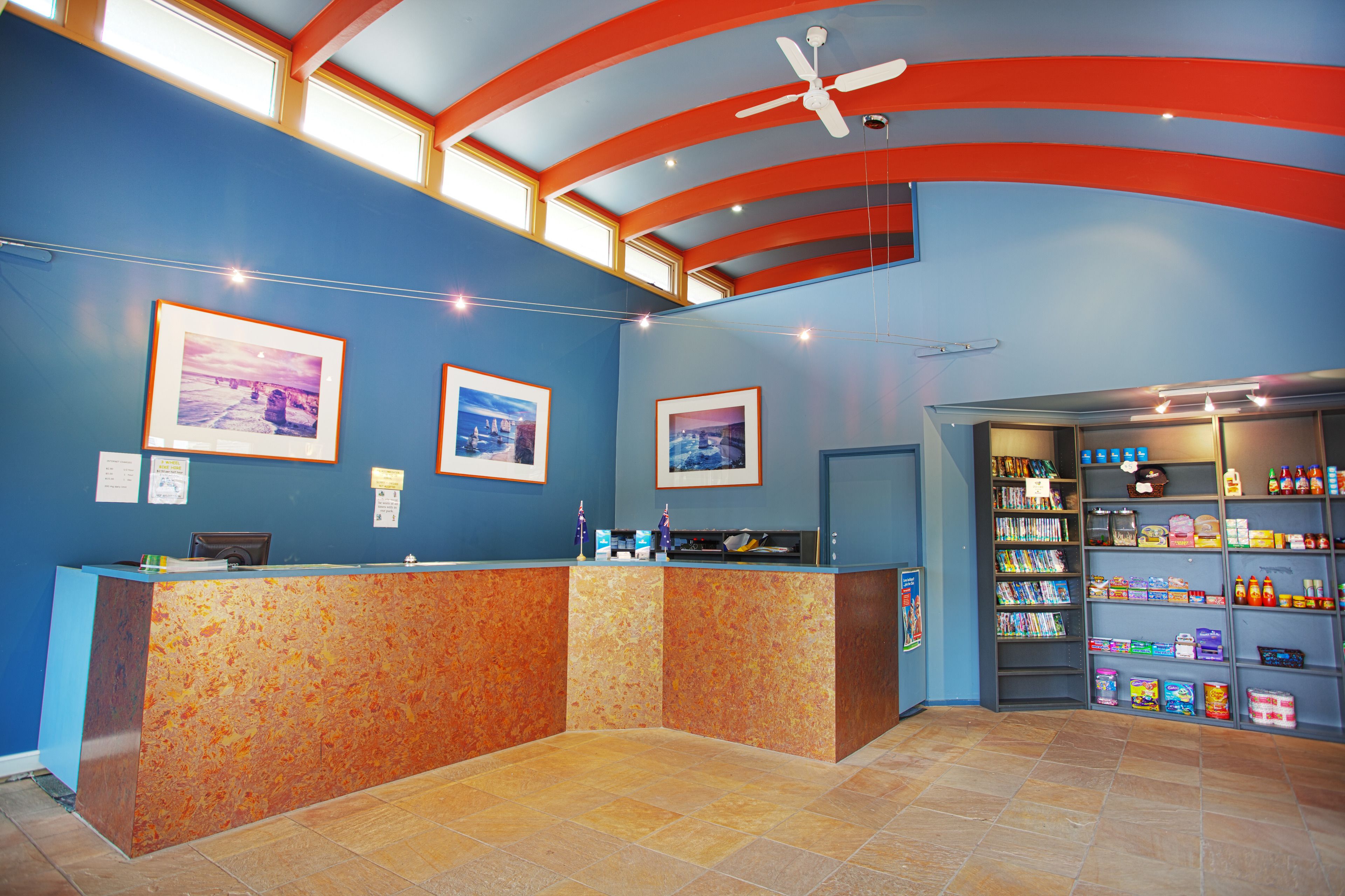 A reception area with a blue wall, two framed pictures, a reception desk, and a shelf with various items.