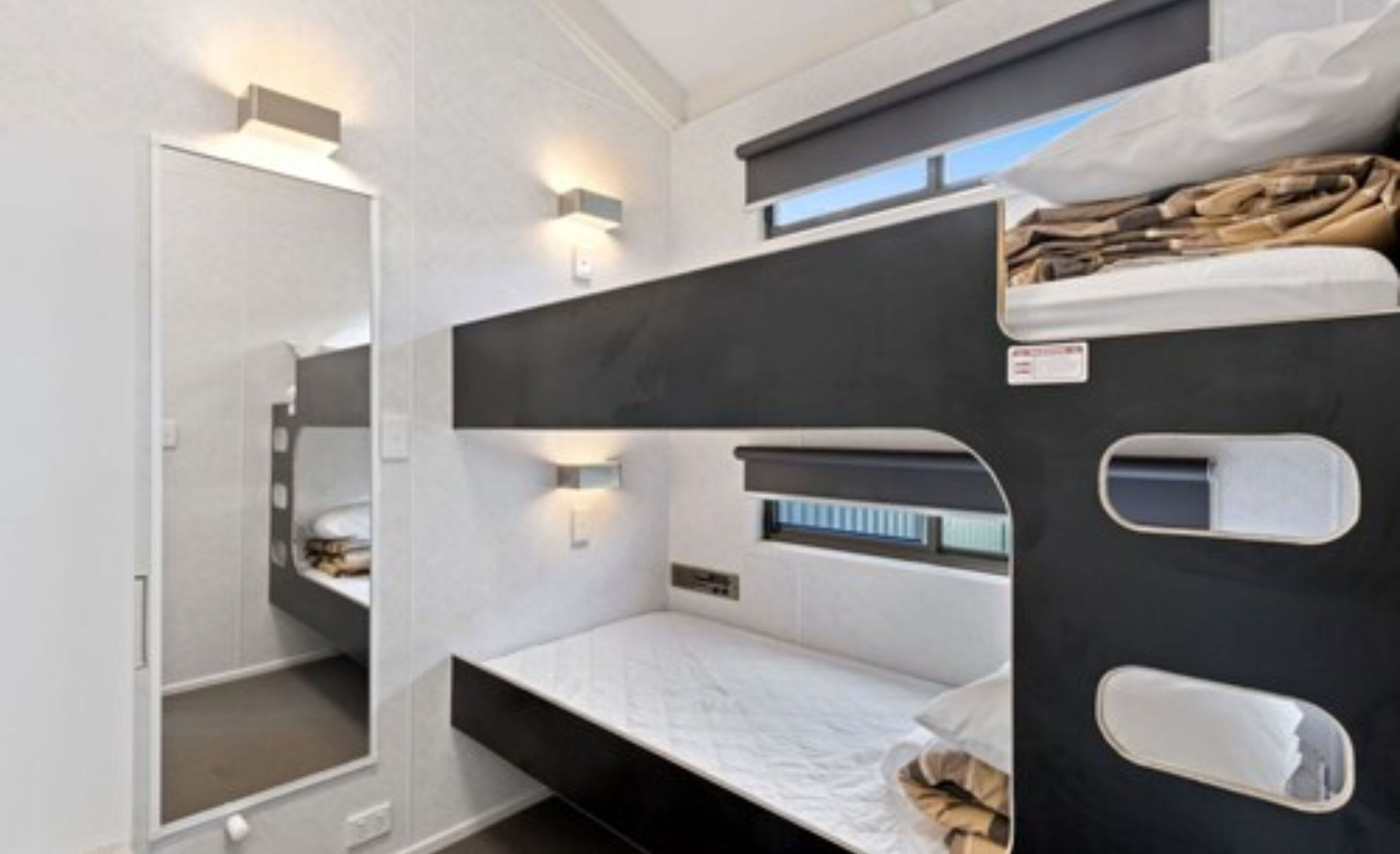 A bunk bed room with a white door, a small window, and a shelf with items.