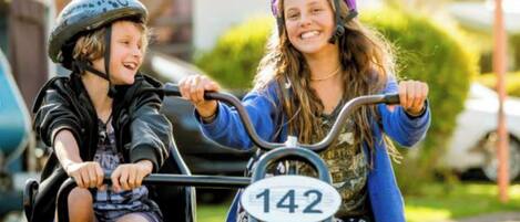 Two children on a tandem bicycle with a visible route number 142.