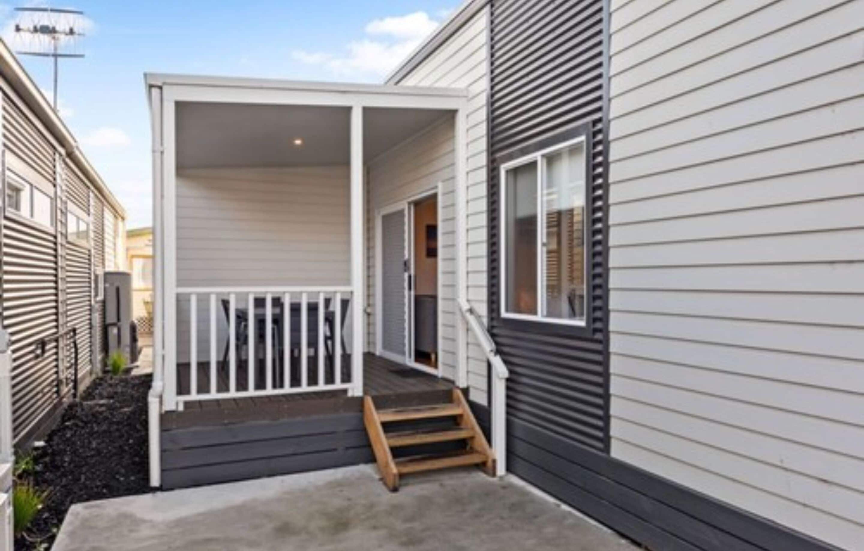 A single-story house with a covered porch and a small set of stairs leading to the entrance.