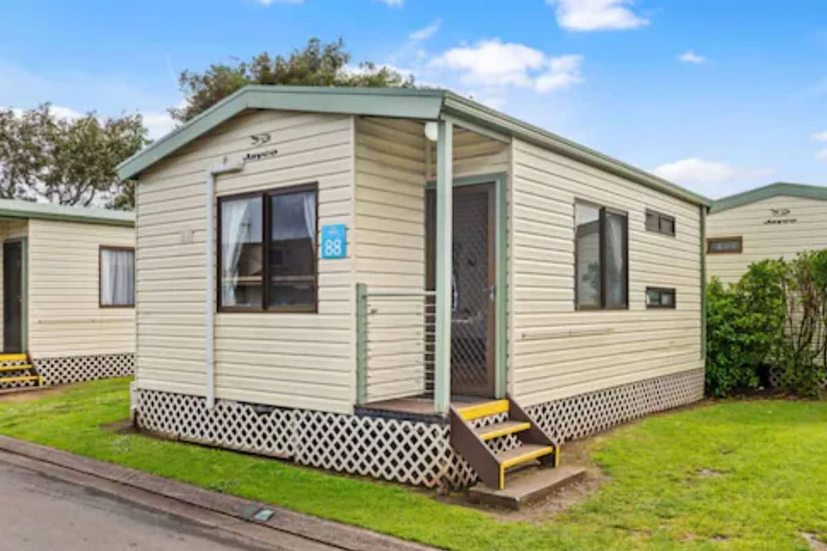 A single-story mobile home with a covered porch and a small front yard.
