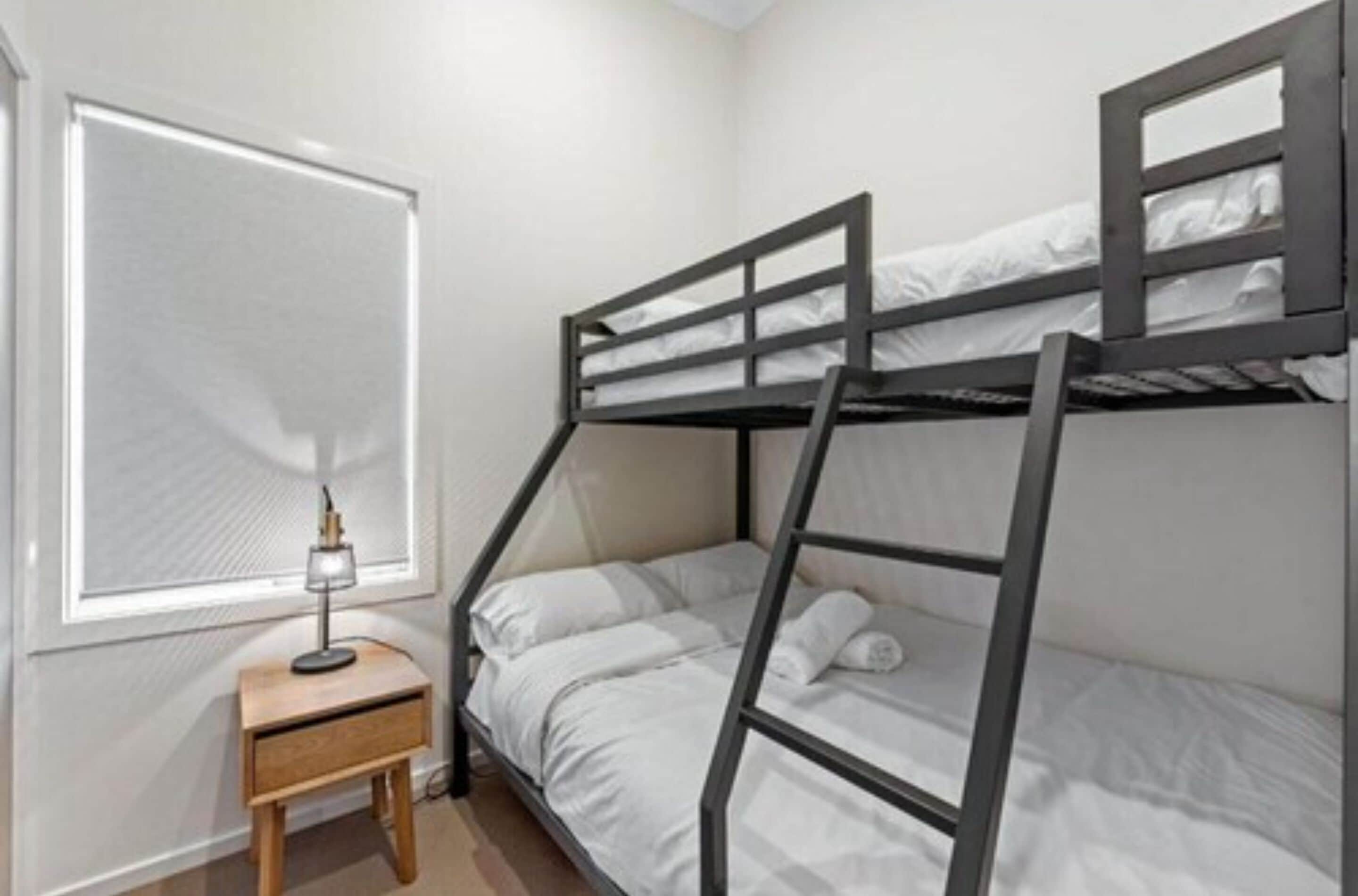 Dormitorio con literas, una mesita de noche pequeña y una lámpara.