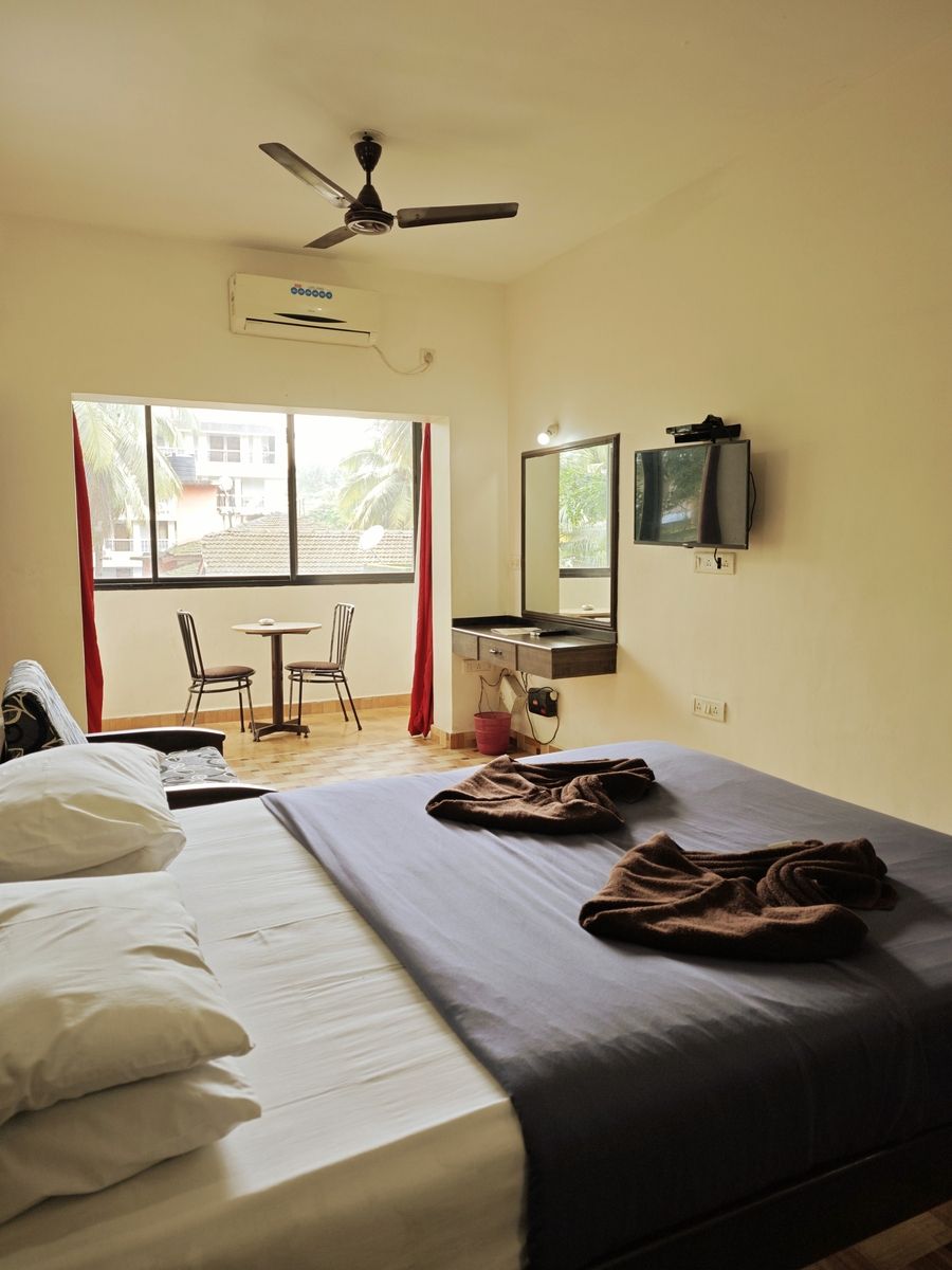 Une chambre d’hôtel avec un lit, un bureau et une chaise, une télévision et une fenêtre avec des rideaux.