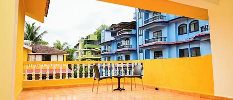 A balcony with a tiled floor, a table, and chairs.