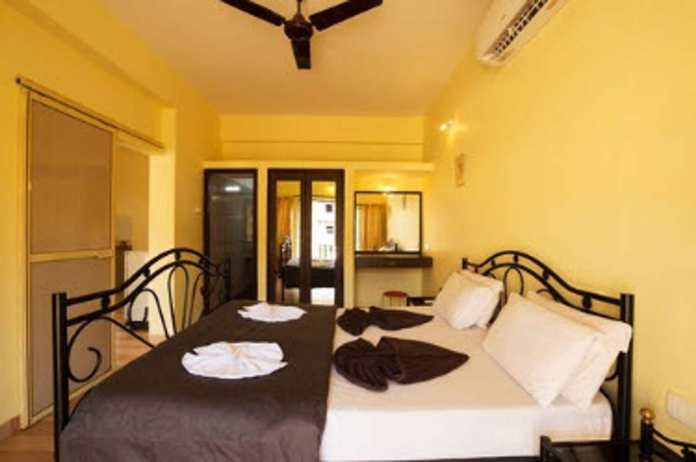Une chambre d’hôtel avec un lit, un ventilateur de plafond et une fenêtre.