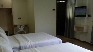 A hotel room with two beds, a desk, a chair, a TV, and a wardrobe. - Merlin Hotel (George Town)
