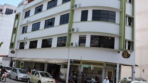 A multi-story building with a white facade and green accents, featuring multiple air conditioning units and a sign for Merlin Hotel. - Merlin Hotel (George Town)