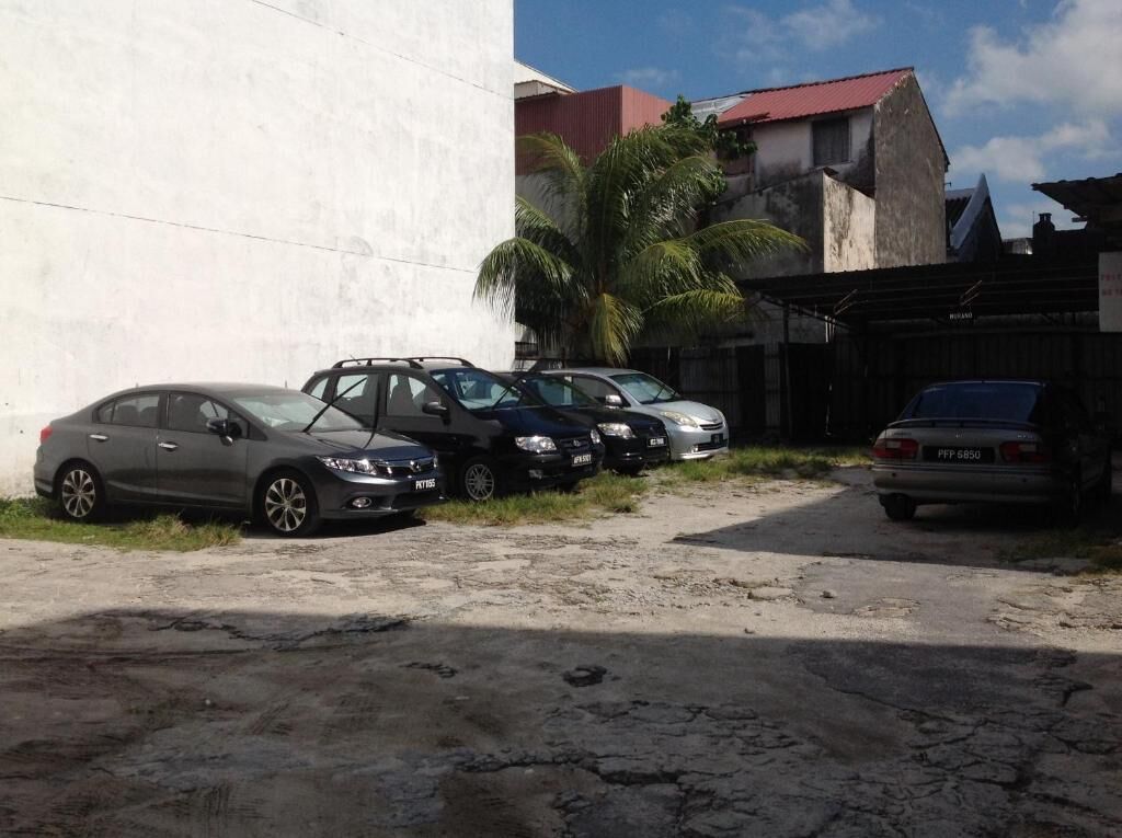 A parking area with several cars parked in front of a building with a red roof.