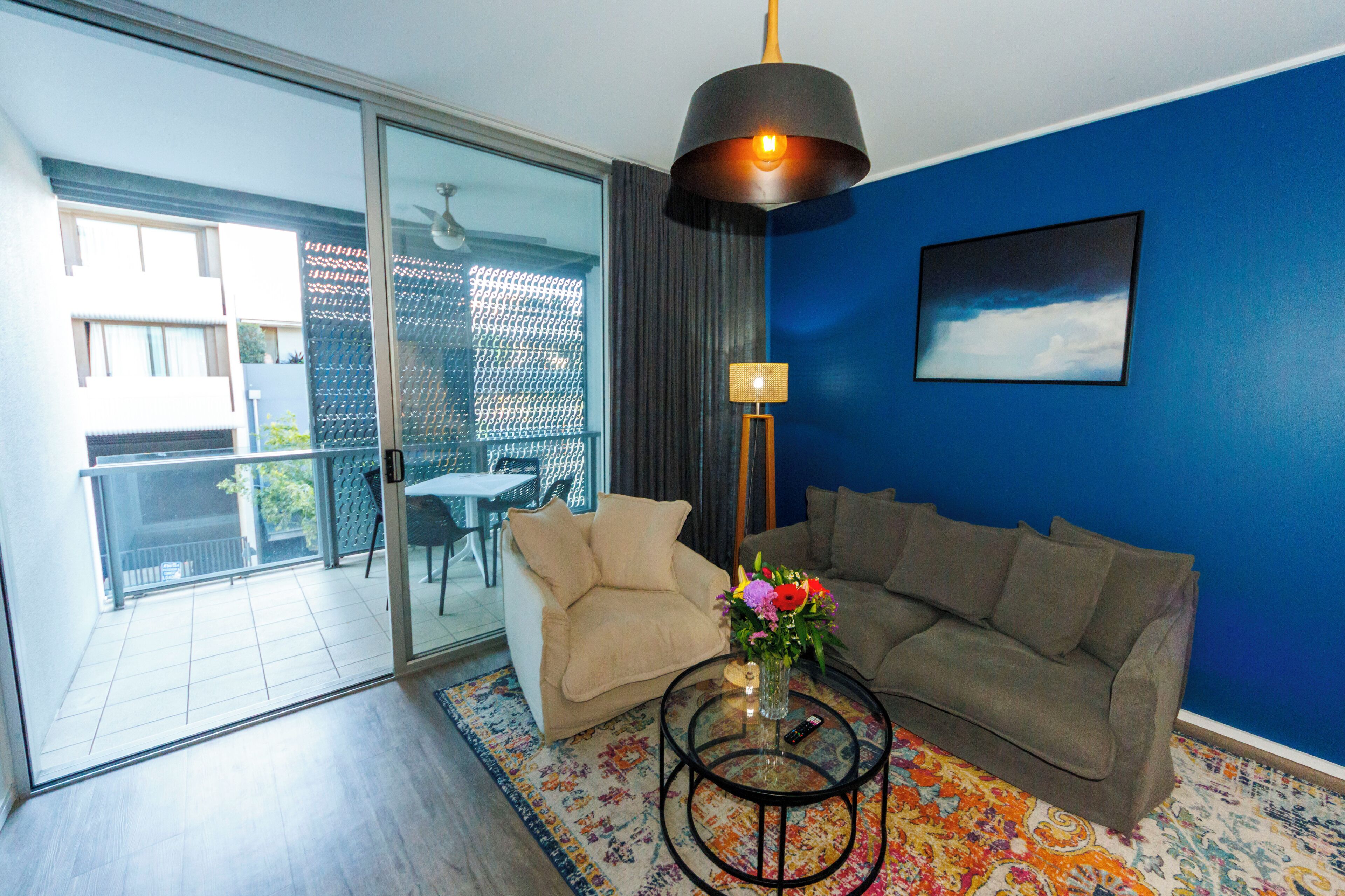 A living room with a sofa, a coffee table, a lamp, and a painting on the wall.