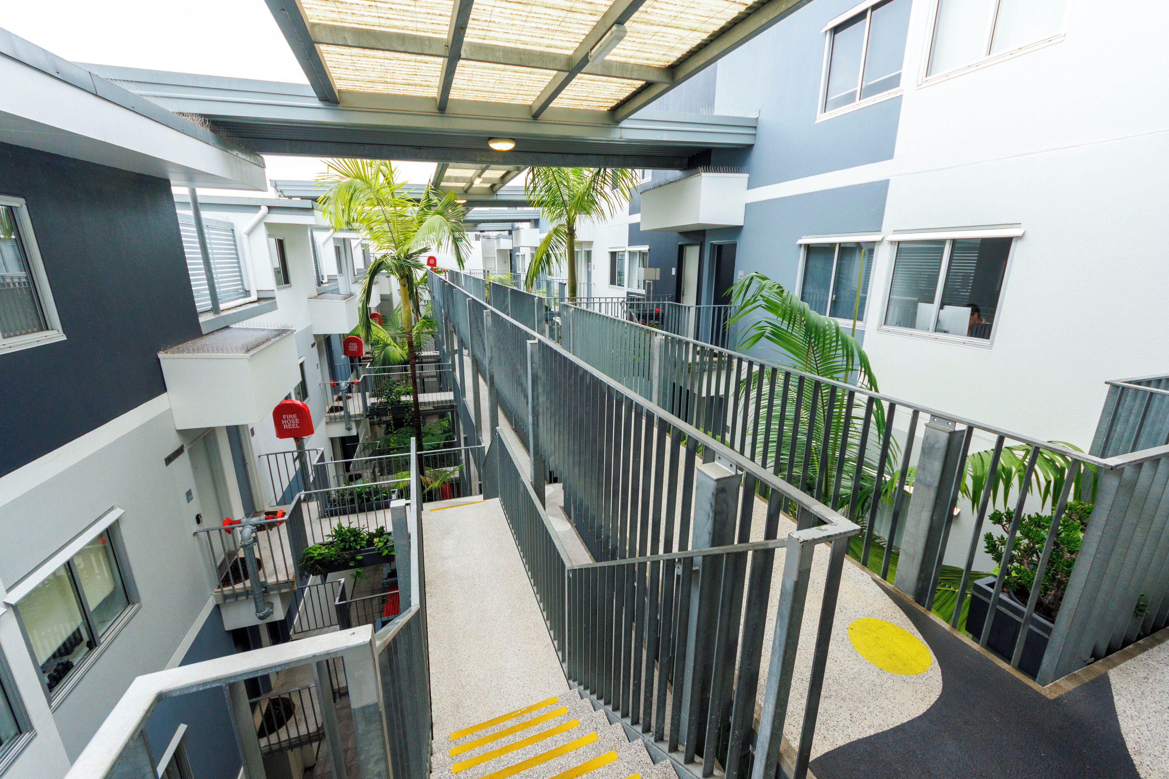 A multi-level residential building with balconies, staircases, and potted plants.