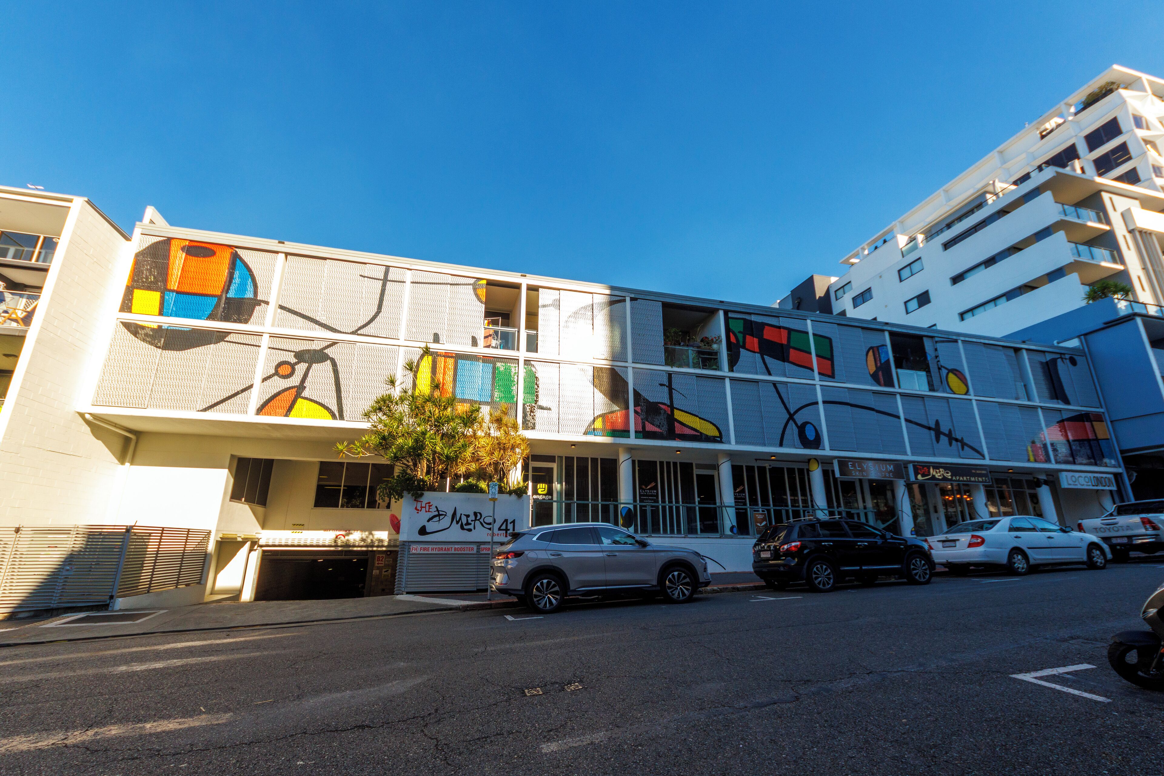 A multi-story building with a modern design, featuring large windows and a colorful mural on the facade.