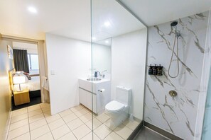 A modern bathroom with a shower, toilet, sink, and a mirror. - Miro Apartments (Fortitude Valley)