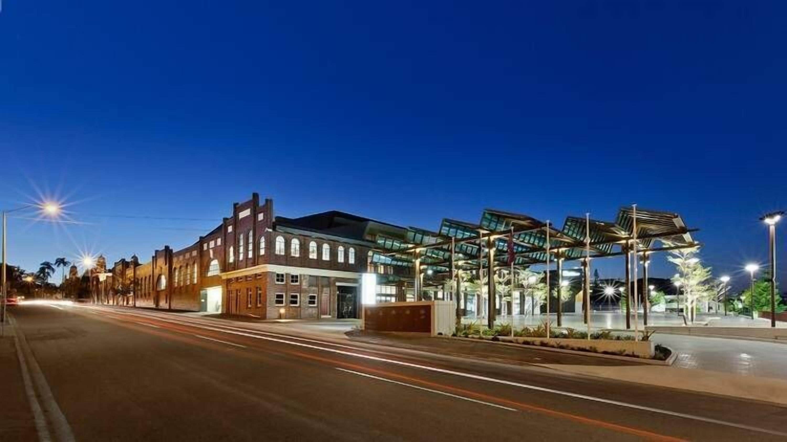 A street view at dusk with a historic building and a modern structure with a glass facade.