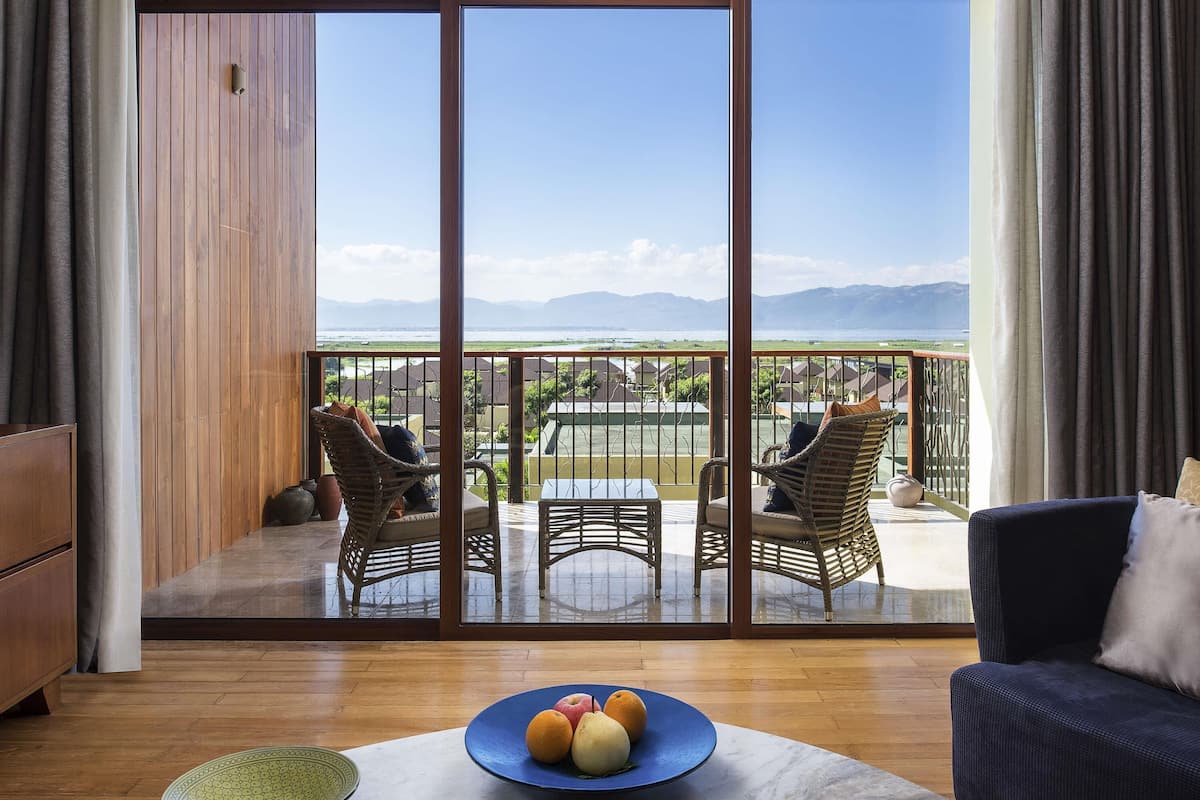 A balcony with wicker furniture, a dining table, and a fruit plate.