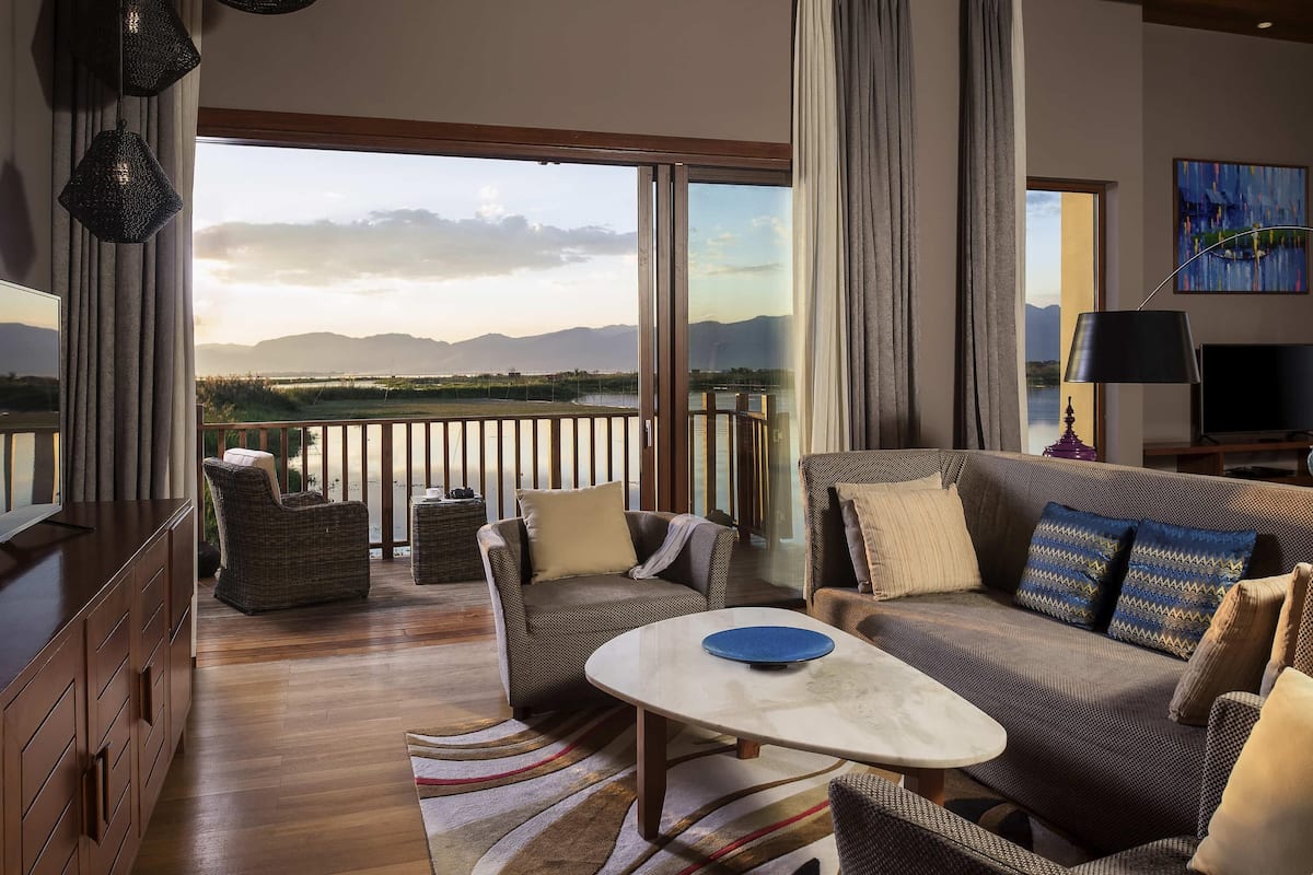 A spacious room with a balcony, wicker furniture, a television, and a painting.