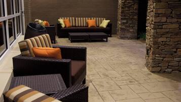 An outdoor seating area with wicker furniture and a stone wall.