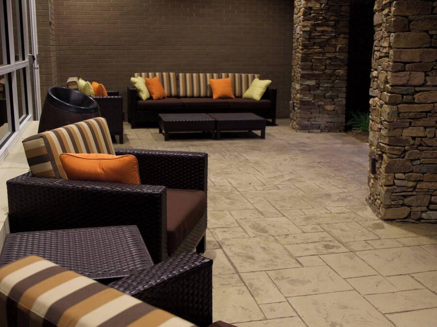 An outdoor seating area with wicker furniture and a stone wall.