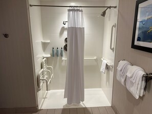 Ein modernes Duschbad mit Glastür, weißem Duschvorhang und Duschbrause.