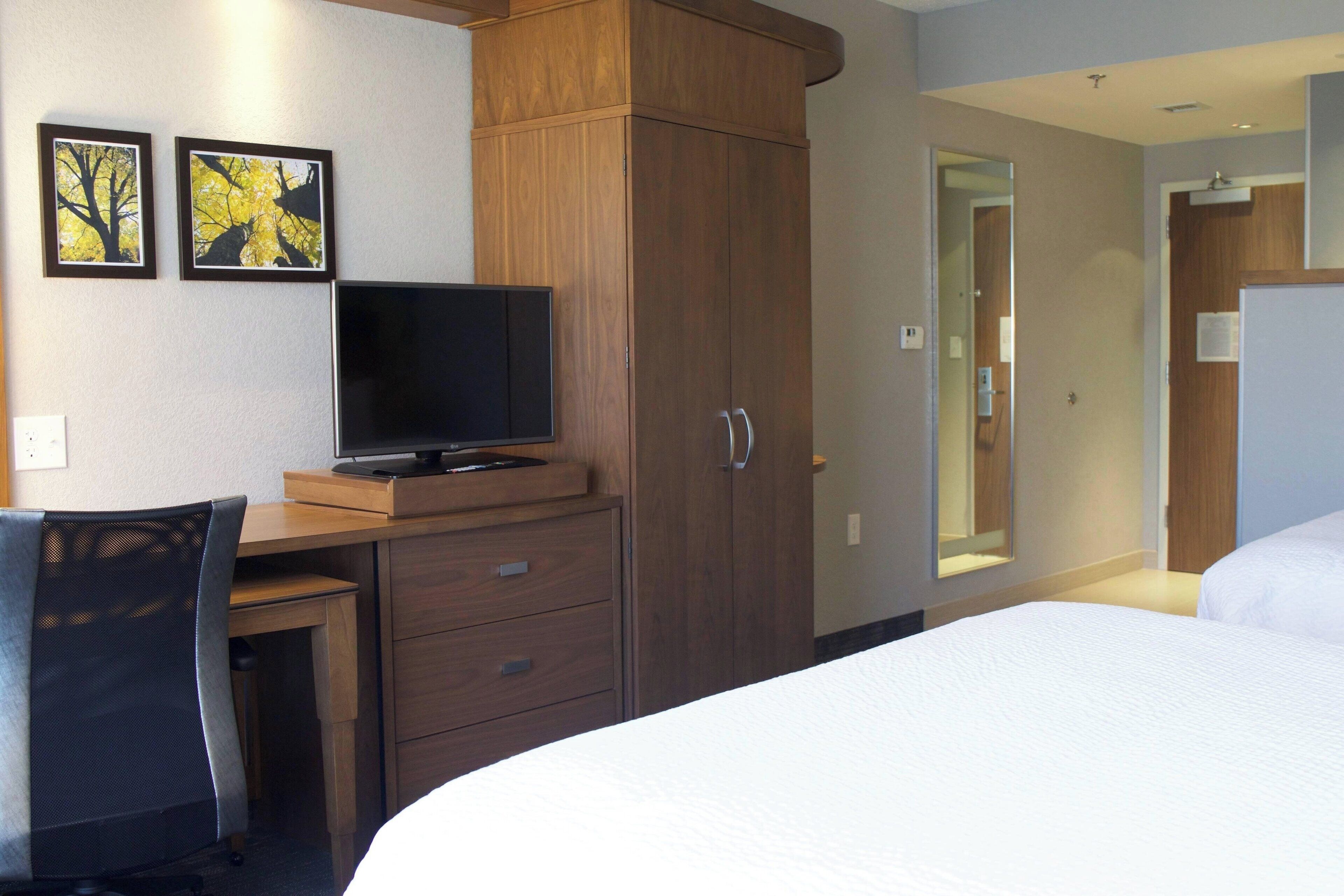 Ein Hotelzimmer mit Bett, Schreibtisch mit Computer, Stuhl und Kleiderschrank.