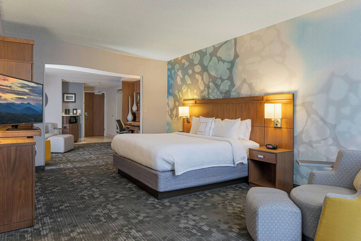 Une chambre d’hôtel avec un grand lit, un bureau, une chaise et un téléviseur.