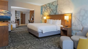 A hotel room with a large bed, a desk, a chair, and a TV.