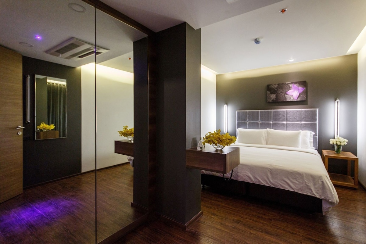 Un dormitorio moderno con una cama grande, mesitas de noche, un espejo y una obra de arte colgada en la pared.