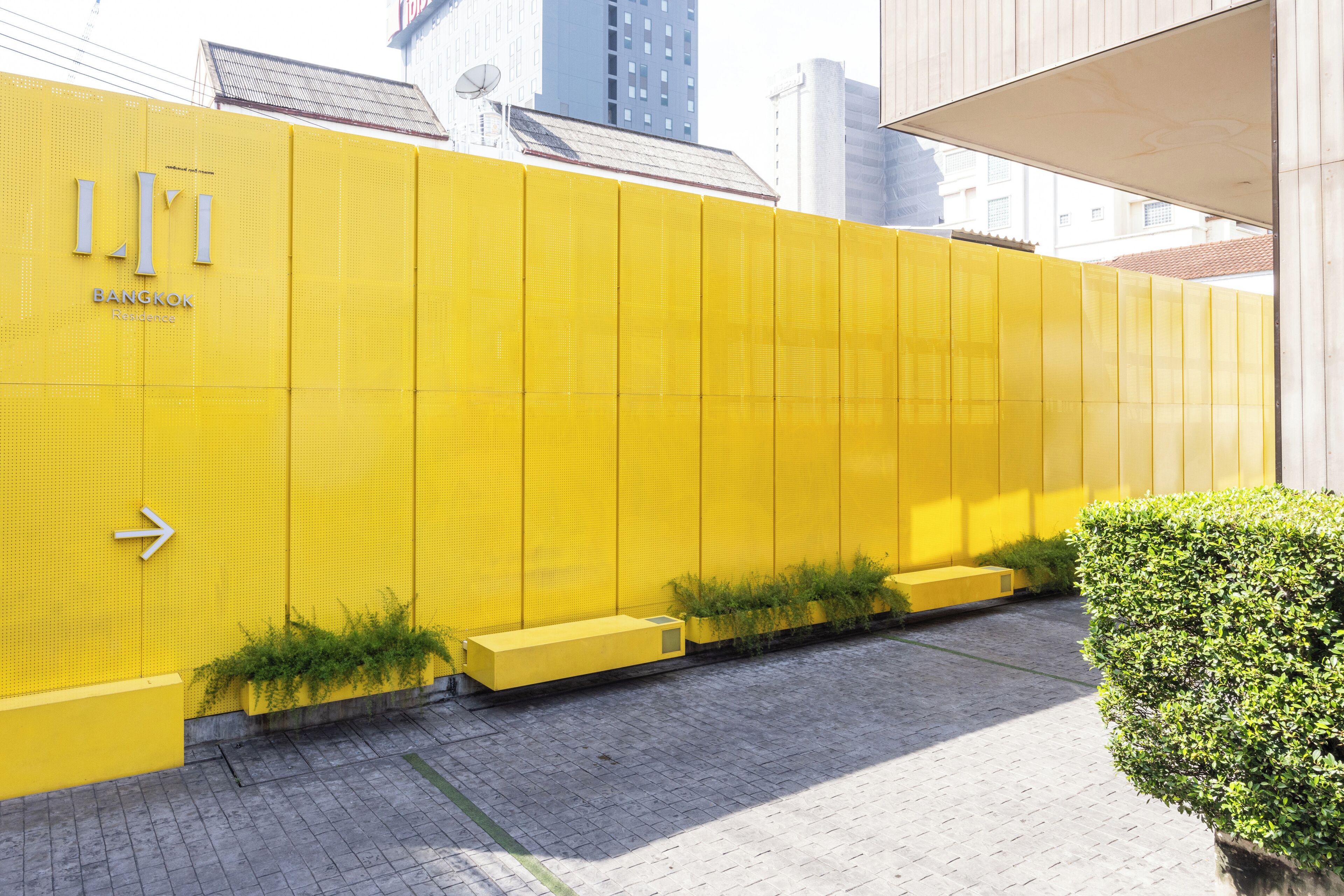 Un edificio amarillo con un cartel que dice 'L.L.L. Bangkok Residence'.