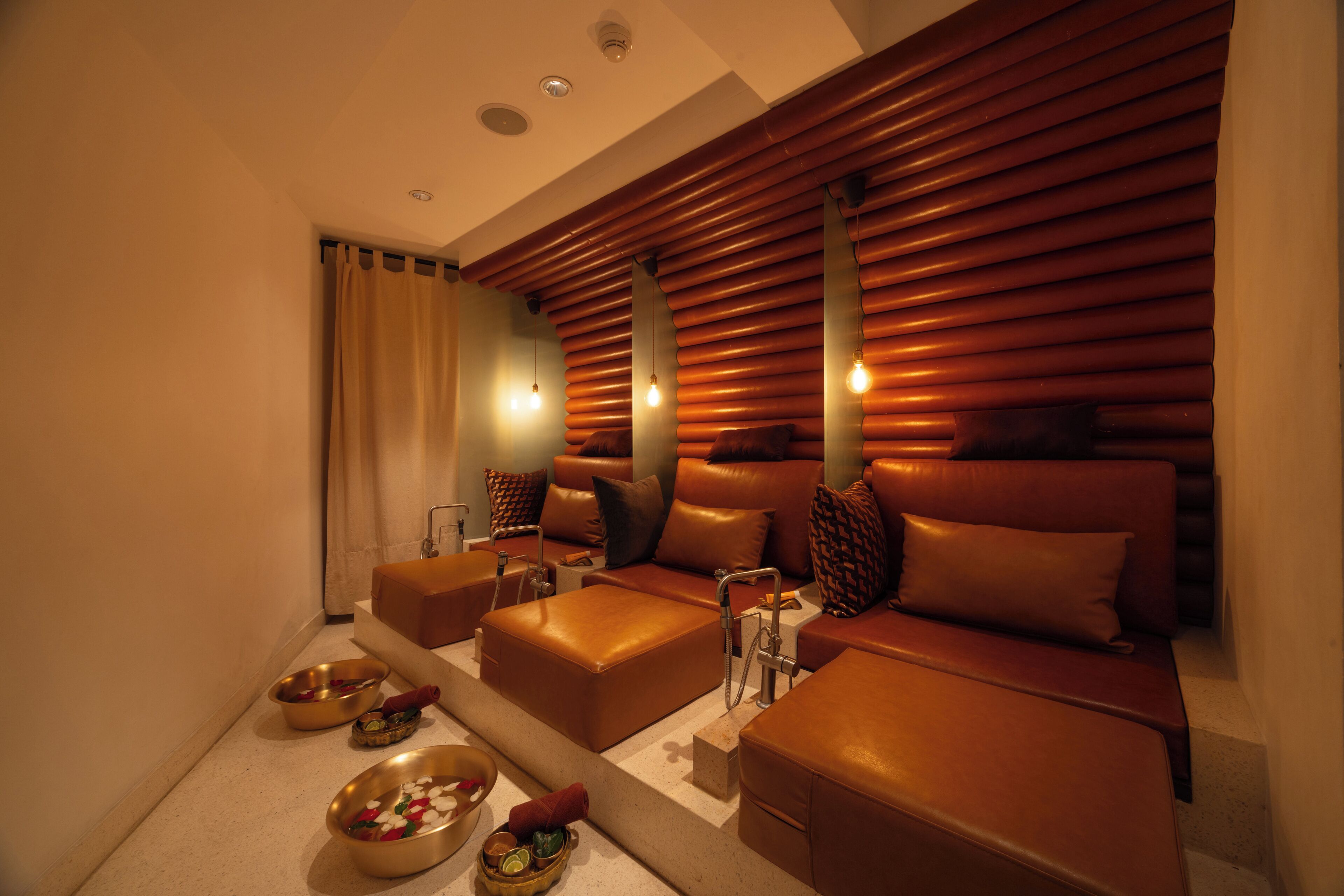 A modern spa room with a sofa, two bowls, and a sink.