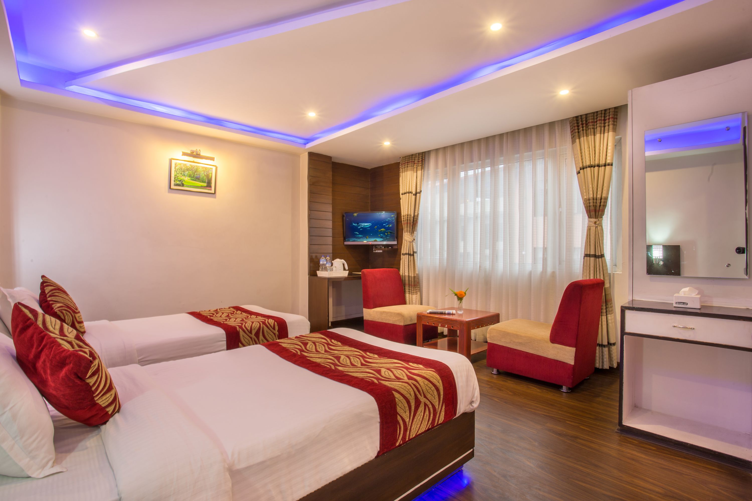 A hotel room with two beds, a TV, a desk, and a chair.