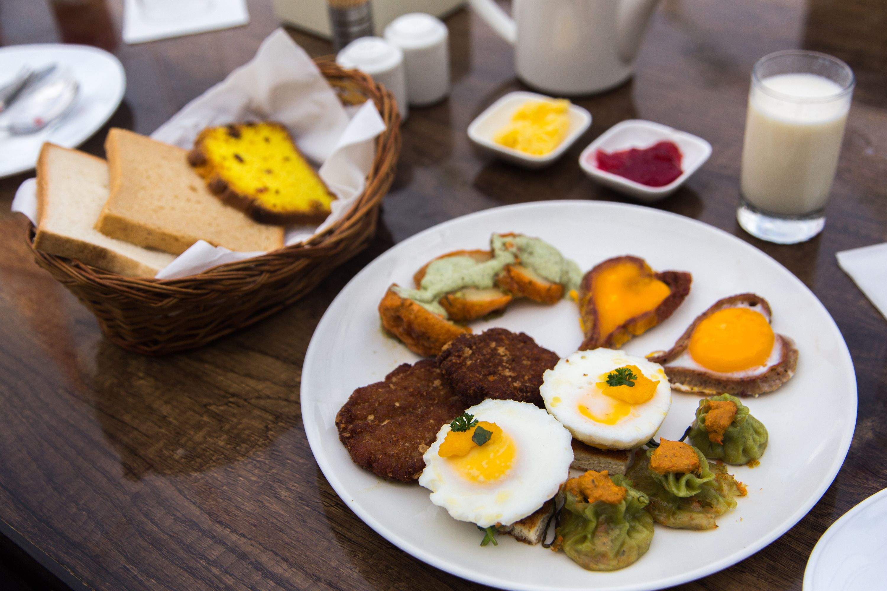 A breakfast plate with eggs, meat patties, and vegetables.