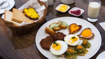 A breakfast plate with eggs, meat patties, and vegetables.