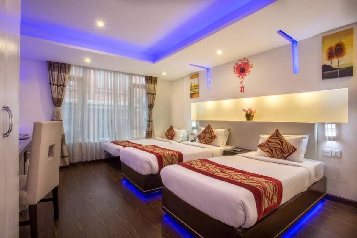 A hotel room with two beds, a desk, and a chair.