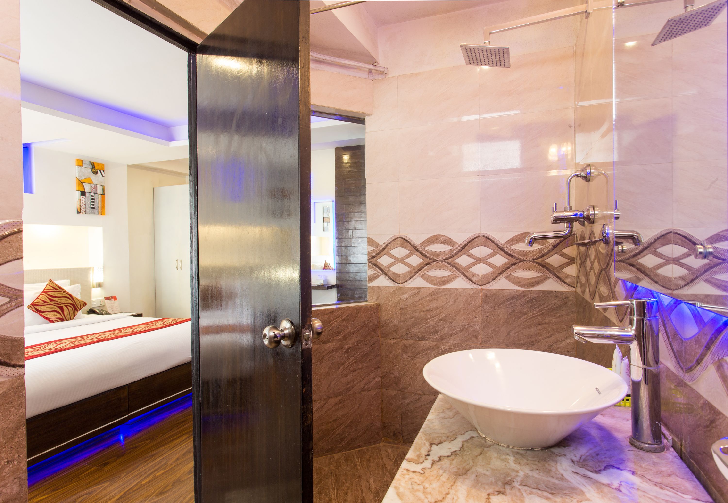 Une salle de bain moderne avec un grand lavabo blanc, une douche et un lit recouvert d’une couette rouge et blanche.