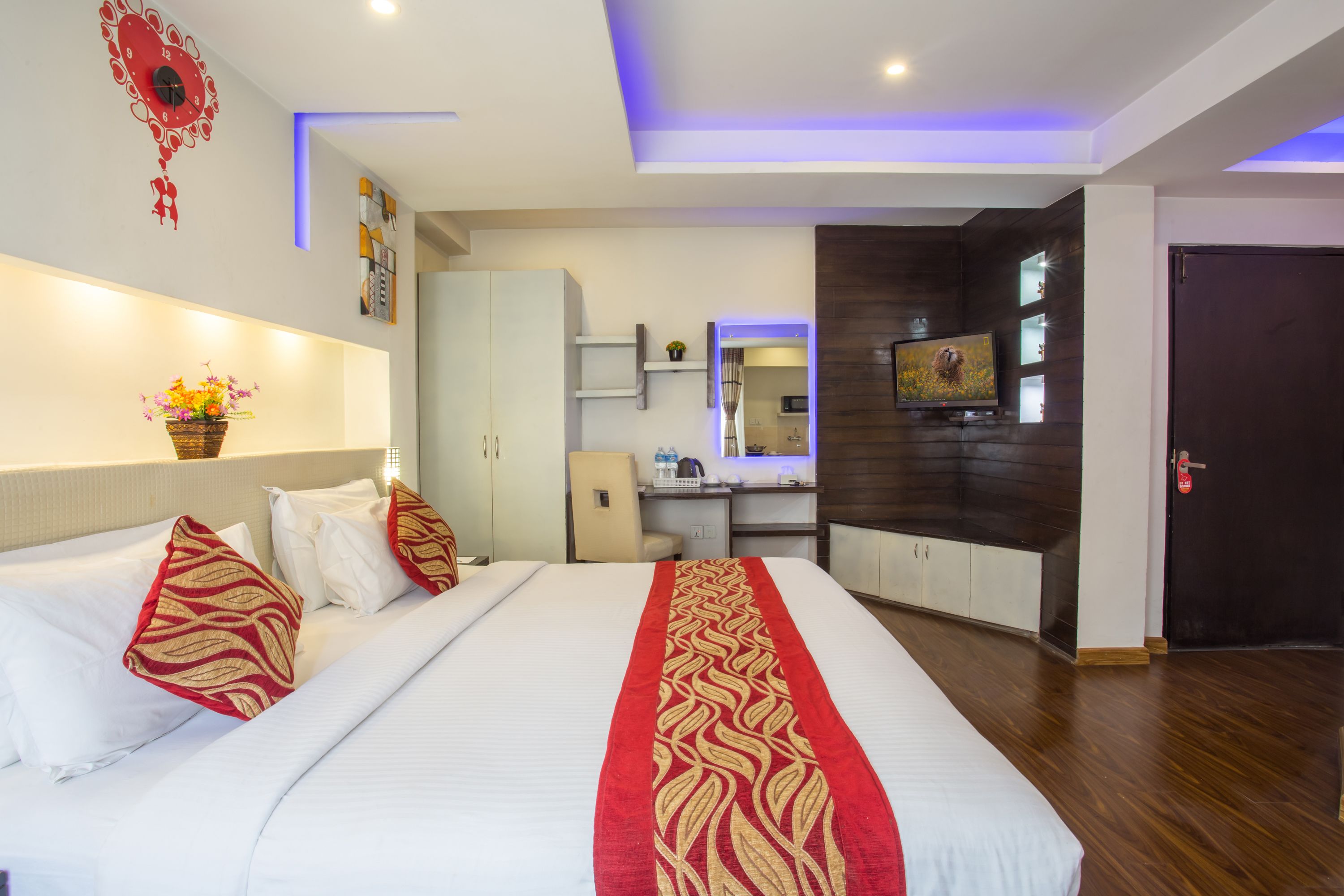Une chambre d’hôtel avec un grand lit, un bureau, une télévision et une salle de bain visible à travers une porte ouverte.