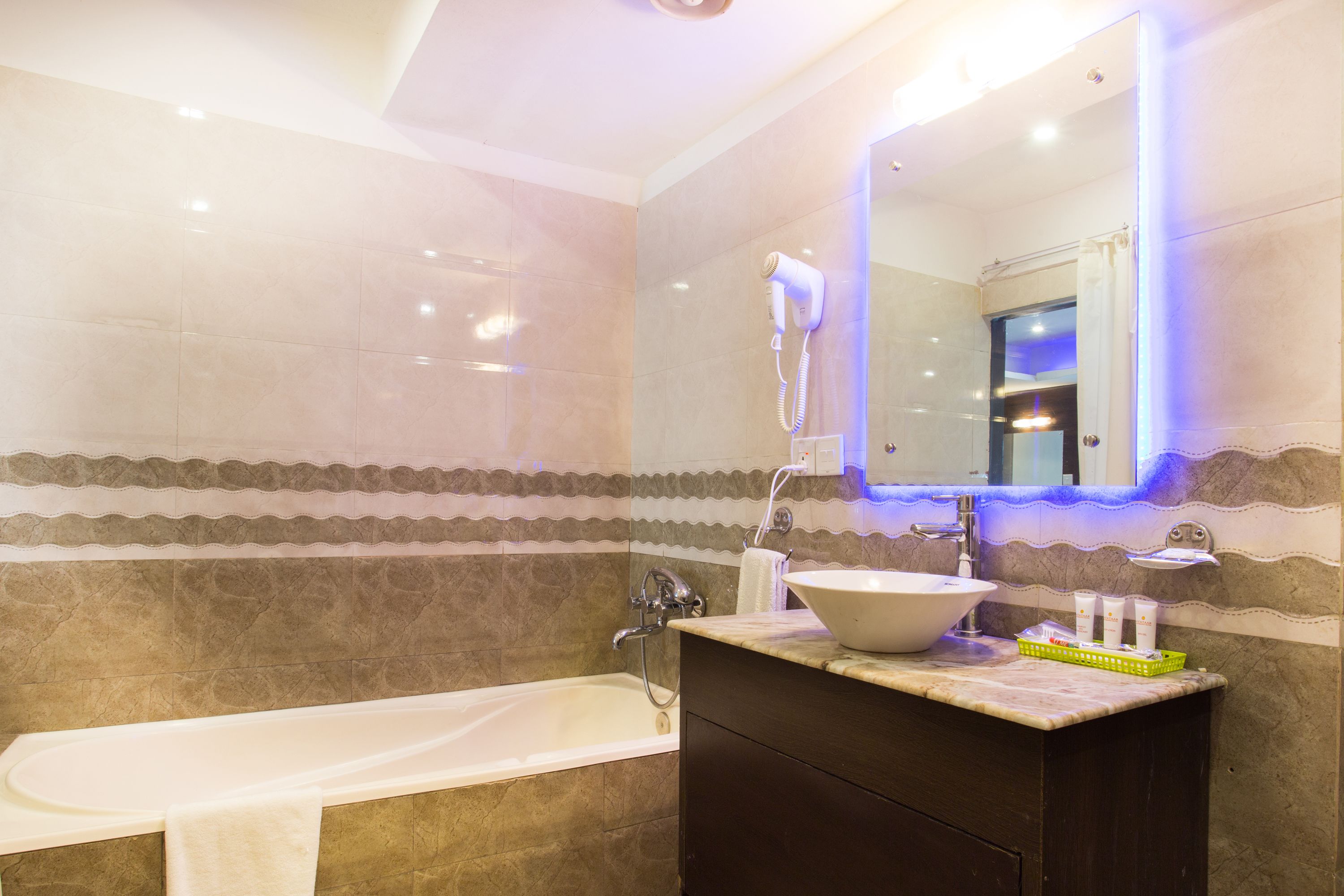 A bathroom with a bathtub, a sink, and a hairdryer mounted on the wall.