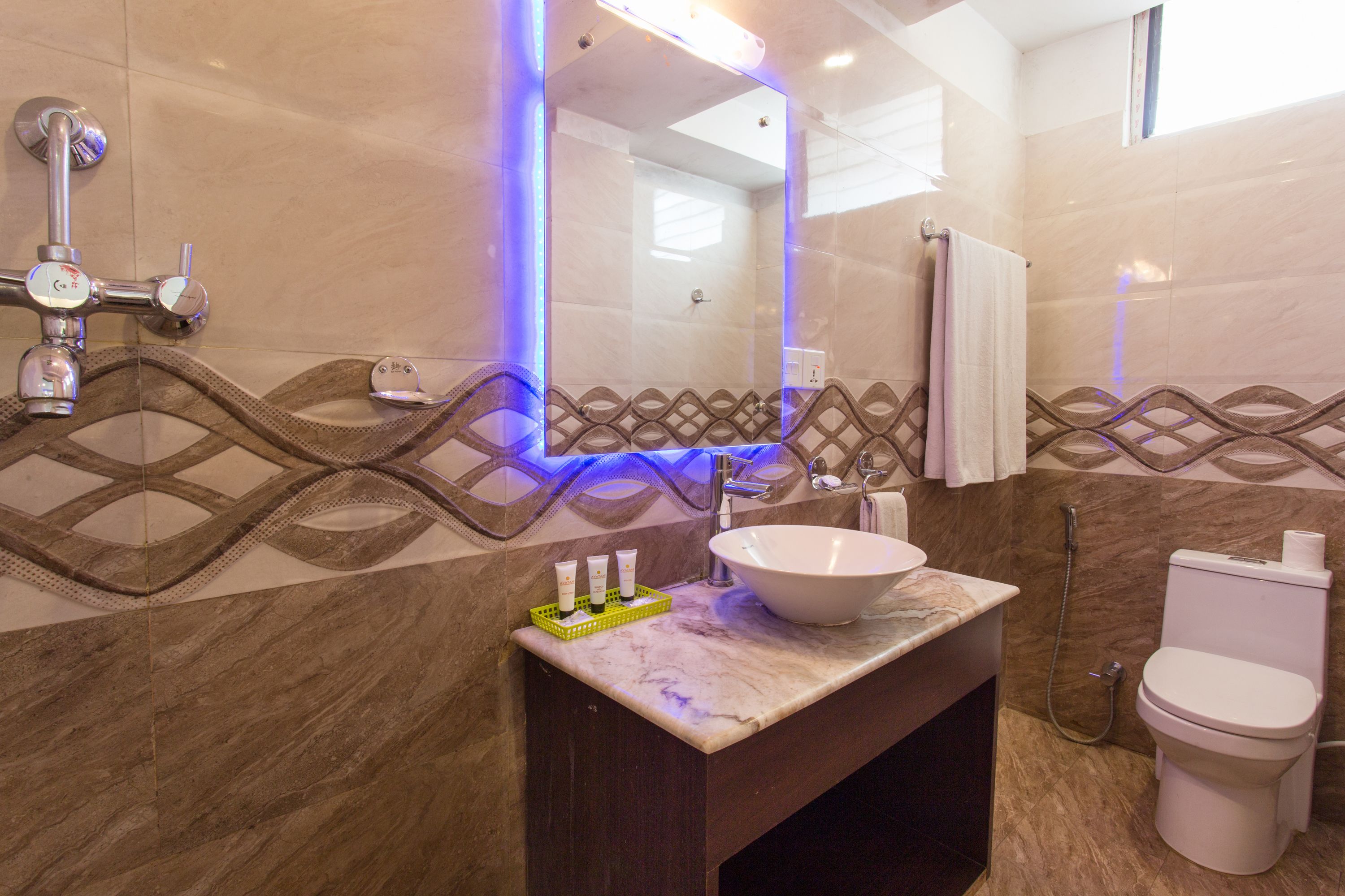 A bathroom with a marble sink, a large mirror, and a toilet.