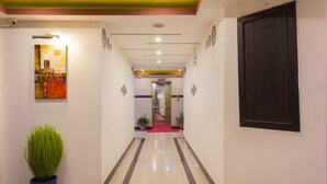 A hotel corridor with a red carpet leading to a door, potted plants, and a wall-mounted artwork. - Avataar Kathmandu Hotel (Kathmandu)